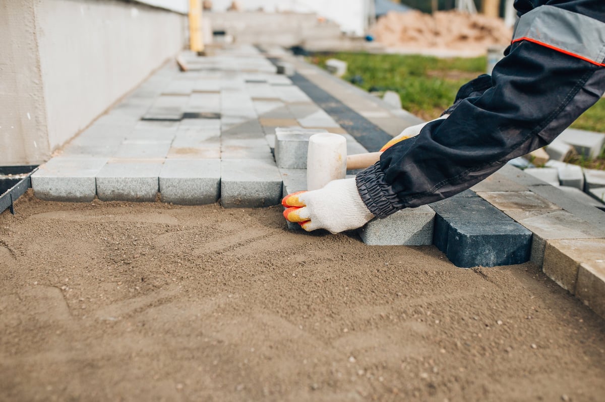 Construction workers laying concrete paving stones for a garden path