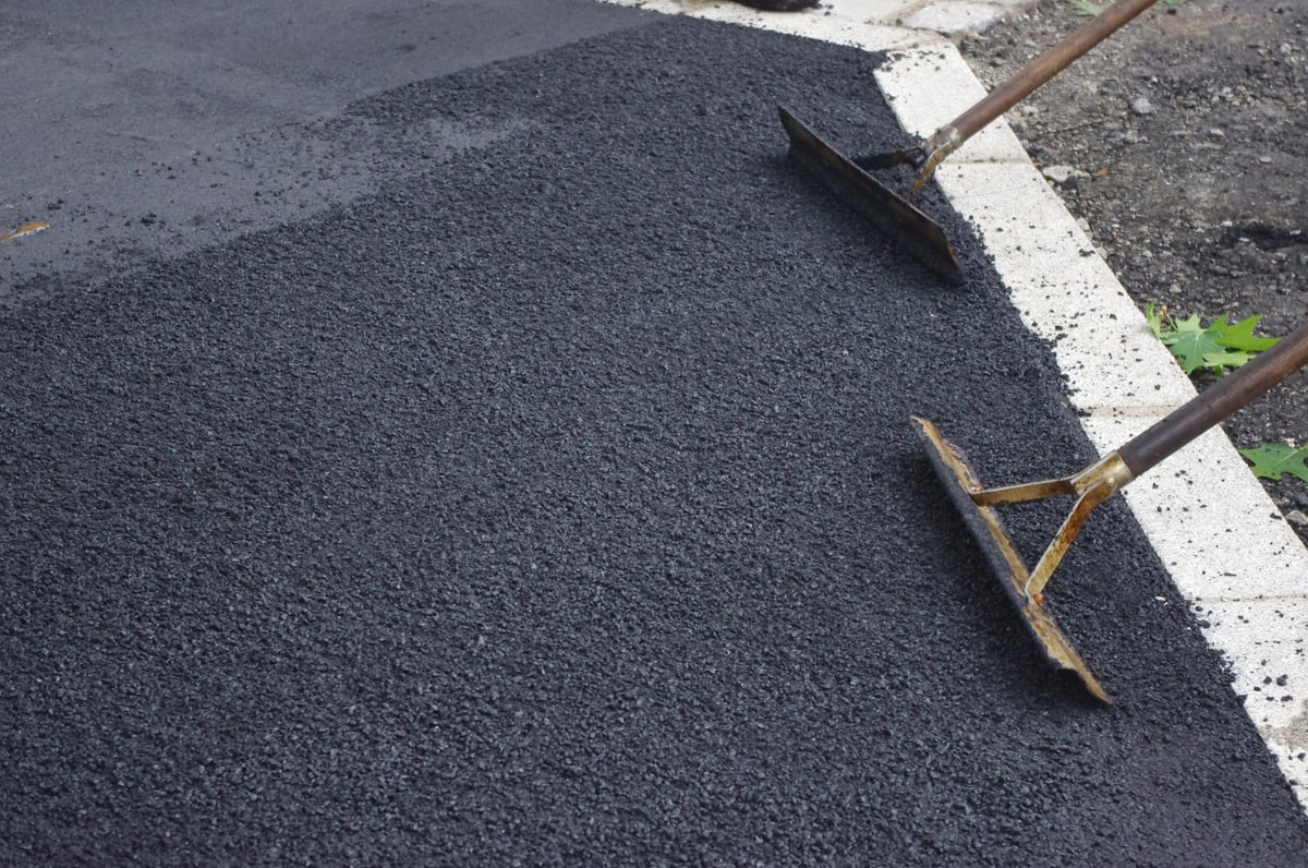 Workers tools on freshly laid dark gravel driveway surface